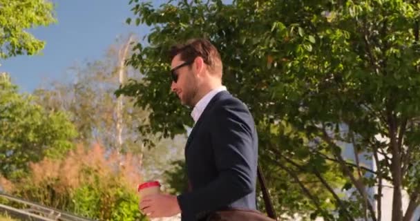 O homem segurando xícara de café andando ao ar livre para trabalhar escritório com rosto sorriso NY — Vídeo de Stock