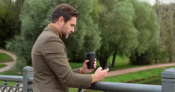 Um cara de terno está esperando por uma garota em um encontro, conhecido, café, ponte — Vídeo de Stock