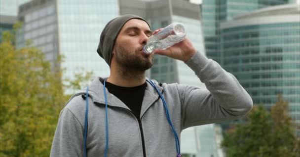 Мускулистый человек пьет воду. Спортсмен в Москве выпил после пробежки — стоковое видео