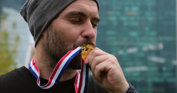 Sportler steht mit drei Goldmedaillen an einer rot-weiß-blauen Schleife — Stockvideo