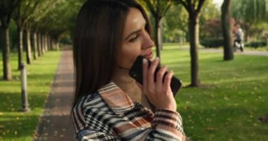 Sonbahar parkına giderken sarı ceketli, gülümseyen çekici kadın.