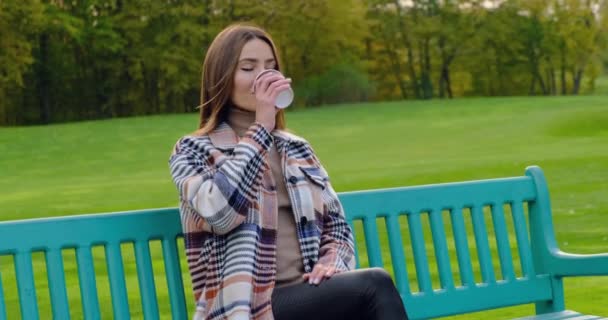 Sonriente atractiva mujer en abrigo con café para ir en otoño banco parque Canadá — Vídeos de Stock