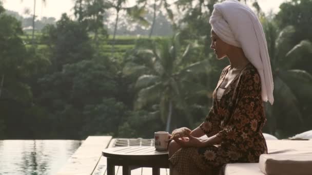Elegáns lány egy fürdőköpenyben reggelizik a trópusi villa reggel Bali — Stock videók