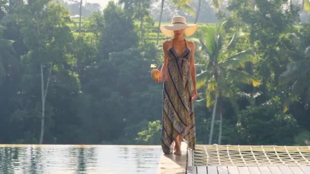 Menina em um vestido elegante está andando perto da piscina com coco na manhã Bali — Vídeo de Stock