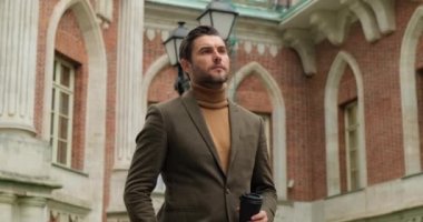 Şık giyinmiş düşünceli yakışıklı iş adamı. Çünkü kahve içiyor ve başka tarafa bakıyor.