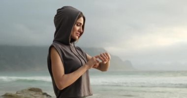 Okyanus kıyısındaki plajda spor yapan kız spor takip cihazını kontrol ediyor. akıllı saat