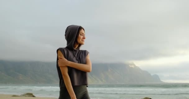 Fille sportive dans un capot se promène le long de la plage près de l'océan après l'entraînement — Video