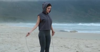 İpe atlayan kendine güvenen genç bir kadın. Okyanusun kenarında sabah sporu