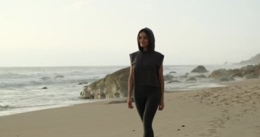 Spor kıyafetli kız okyanus dalgalarının sesinin tadını çıkarıyor.