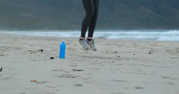 Zelfverzekerde jonge vrouw die op touw springt. Vroeg in de ochtend training door de oceaan — Stockvideo