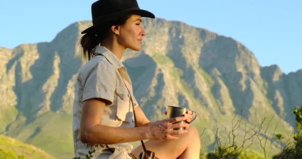 Mulher sentada no penhasco da montanha desfrutando da vista deslumbrante do horizonte do mar — Vídeo de Stock