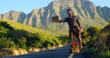 Kafkasyalı turist gün batımında turist çantasıyla yolda otostop çekiyor.