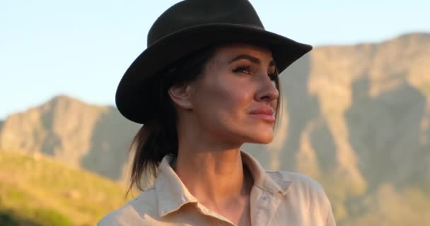 Close-up rosto do viajante em um chapéu de cowboy sentado no pico da montanha bebe água — Vídeo de Stock