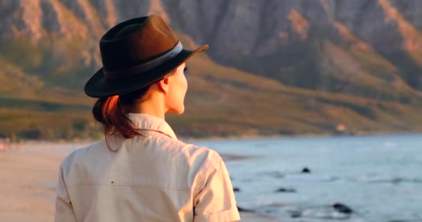 Chica mochilero viajero disfruta con viento fresco del océano. viajero se sienta en una piedra — Vídeos de Stock