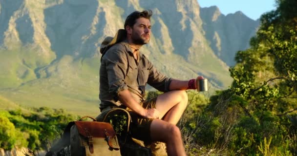 Hombre sentado en el acantilado de montaña disfrutando de la impresionante vista del horizonte del mar — Vídeos de Stock
