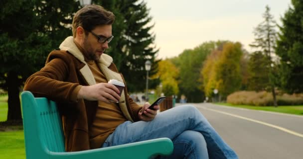 Zakenman op Park Bench met koffie met behulp van mobiele telefoon op de stad Park Canada — Stockvideo