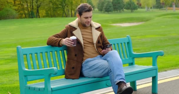 Zakenman op Park Bench met koffie met behulp van mobiele telefoon op de stad Park Canada — Stockvideo