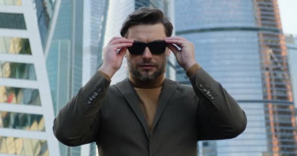 Hombre de negocios en un traje con un peinado elegante se quita las gafas de sol — Vídeos de Stock