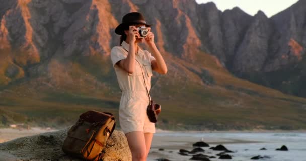 Tourist with backpack in african safari style near the ocean beach takes a photo — Stock videók