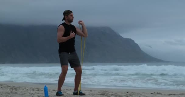 Joven hombre estiramiento con resistencia banda al aire libre botella de agua — Vídeos de Stock