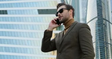 Genç işadamı telefonda şehrin duvarına bakarken yüzünü çeviriyor.