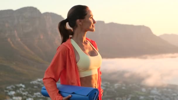 Deportista mirando hacia otro lado mientras está de pie con estera de yoga junto al mar por la mañana — Vídeos de Stock