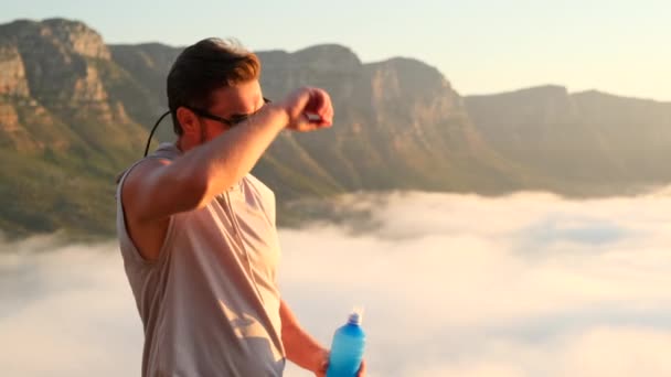 Hombre atlético bebiendo agua de una botella en las montañas después del entrenamiento. — Vídeos de Stock