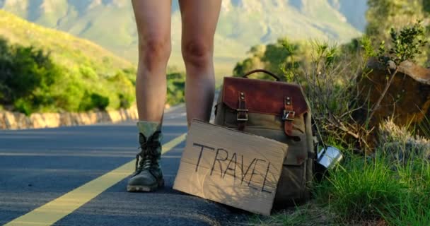 Jolie jeune femme auto-stop touristique le long d'une route. jambes gros plan — Video