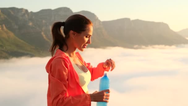 Donna atletica che beve acqua da una bottiglia in montagna dopo l'allenamento. — Video Stock