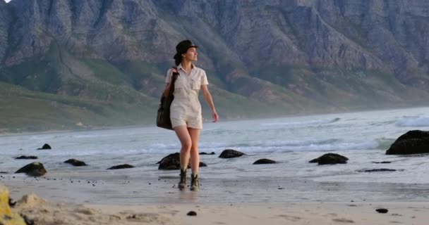 Yürüyüş takımlı bir gezgin kız ve sahilde yürüyüş botları. — Stok video