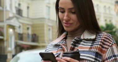 Sokak kahve içme ve cep telefonuyla duran genç kadın