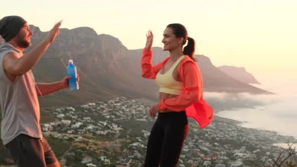 Спортивна пара після ранкової пробіжки в горах насолоджується сонцем — стокове відео