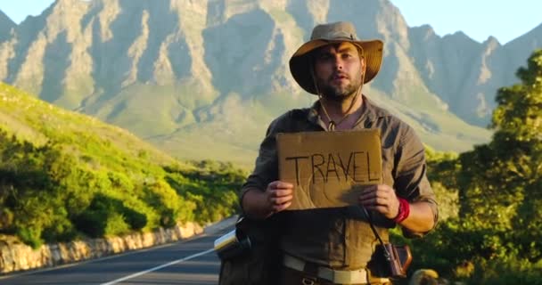 Young caucasian tourist hitchhiking along a road in sunset. — Stock Video