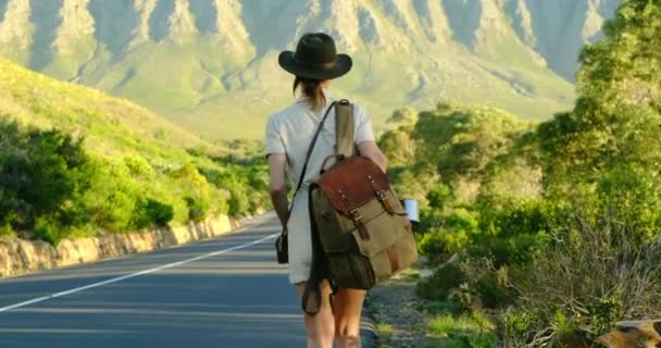 Девушка-путешественница с рюкзаком ходит по шоссе автостопом по Америке — стоковое видео