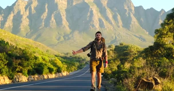 Un hombre viajero con una mochila camina por la carretera, haciendo autostop en América — Vídeo de stock