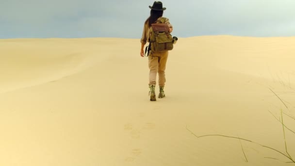 Turista em estilo safari caminha pelo deserto arenoso, o sol escaldante brilha — Vídeo de Stock