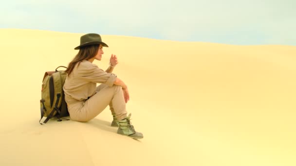 Chica viajera sentada en una duna en el desierto. Sin agua y energía. — Vídeos de Stock