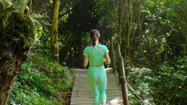 Красивая атлетическая женщина с тонким телом бежит по дорожке в парке — стоковое видео