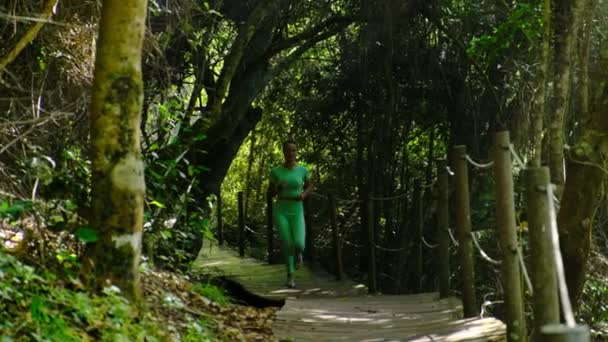 Bella donna atletica con un corpo sottile corre lungo il percorso nel parco — Video Stock
