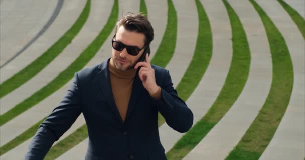 Stylish guy in a blue suit speaks on the phone near the business center — Video Stock