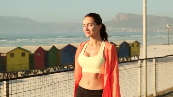 A beautiful slender girl walks along the beach after a morning run — Stockvideo