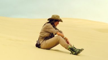 Woman feels thirst and drink water in the desert. holding the sand in his fist