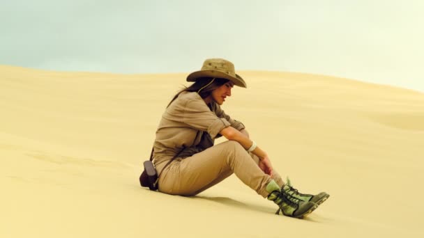 Vrouw voelt dorst en drinkt water in de woestijn. het zand in zijn vuist houden — Stockvideo