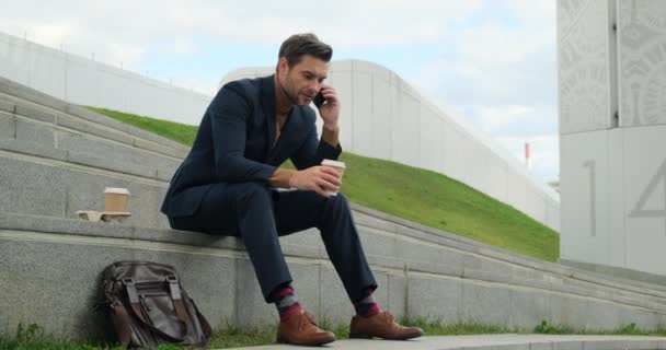 Successful mature businessman talking on mobile phone outside business center. — Αρχείο Βίντεο