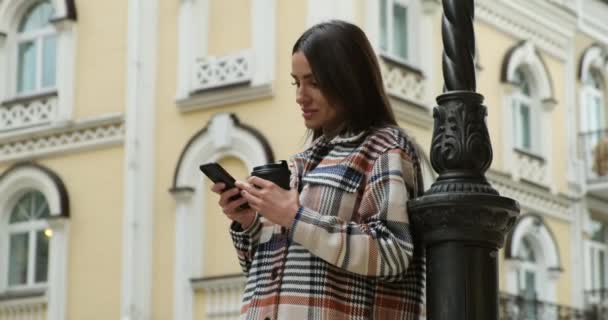 Attraktiv ung kvinna med kopp te eller kaffe med hjälp av smartphone — Stockvideo