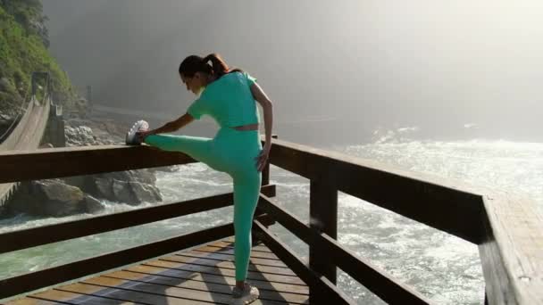 Esbelta chica en un traje de turquesa entra para los deportes por la mañana en la orilla — Vídeos de Stock