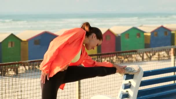 Сильна і красива спортивна дівчина в спортивній манері простягається на пляжі — стокове відео