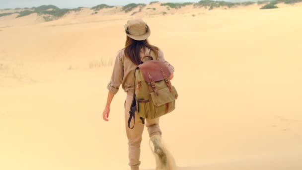 少女はサハラ砂漠で砂と遊ぶ 独身女性は日没時にサハラ砂漠で砂を投げます 灼熱の太陽の下砂漠を砂の上を歩く太陽から帽子を被った少女旅行者 — ストック動画