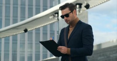 Güneş gözlüklü bir adam tabletle kontrat imzalıyor. İş ve teknoloji kavramı. Düşünceli bir adam elinde kalemle başka yere bakıyor. Sokaklarda çalışan bir web tasarımcısı. Genç mimar inşaat kontrolü yapıyor.
