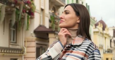 Uzun saçlı mutlu kadın bir kafede cappuccino içiyor. Soğuk kışta sokakta poz veren güzel esmer kız elinde kahve ve kruvasan yemeği, gülümseyerek tek başına eğleniyor.